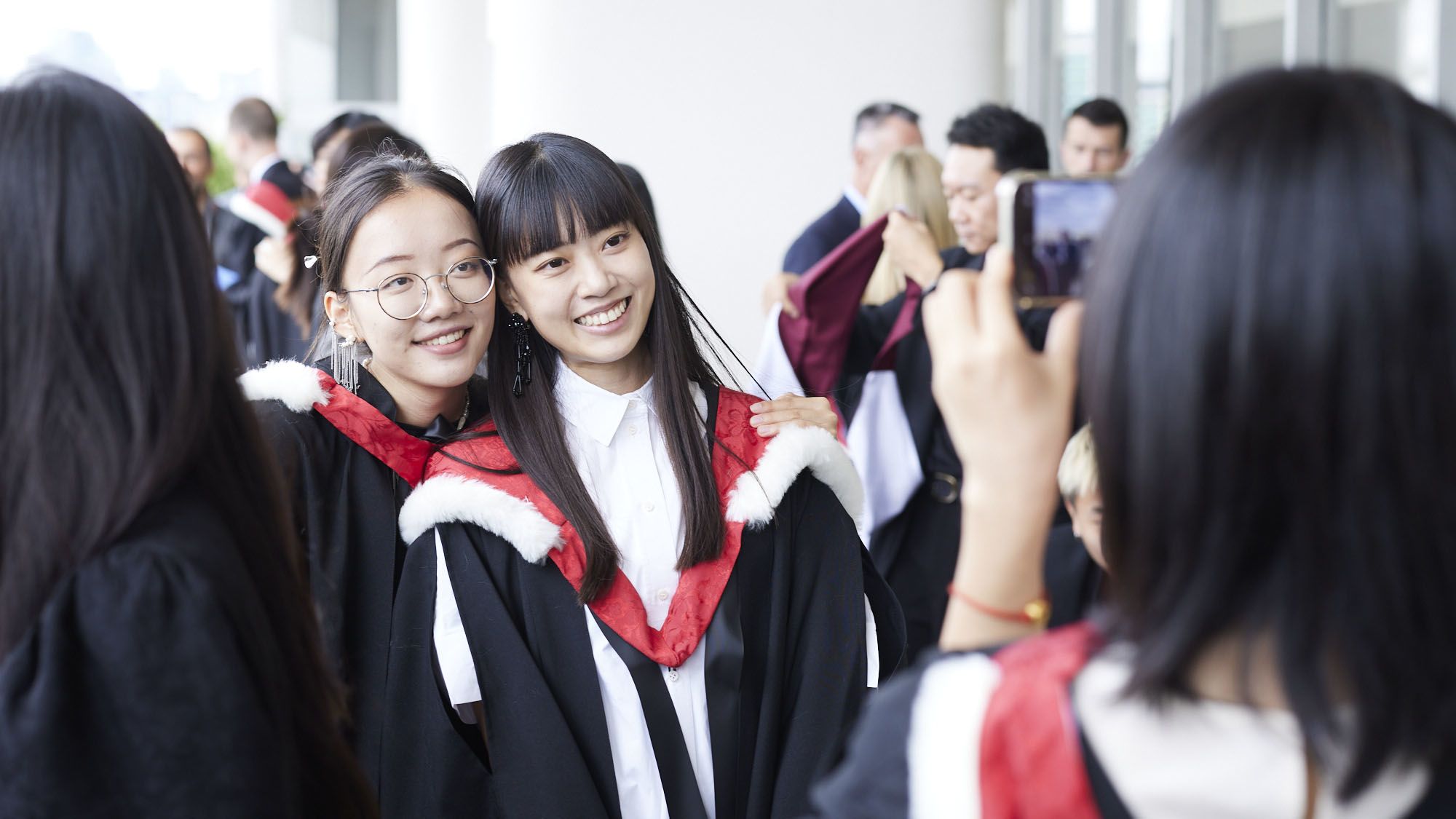 Two convocation students with a bunch of flowers