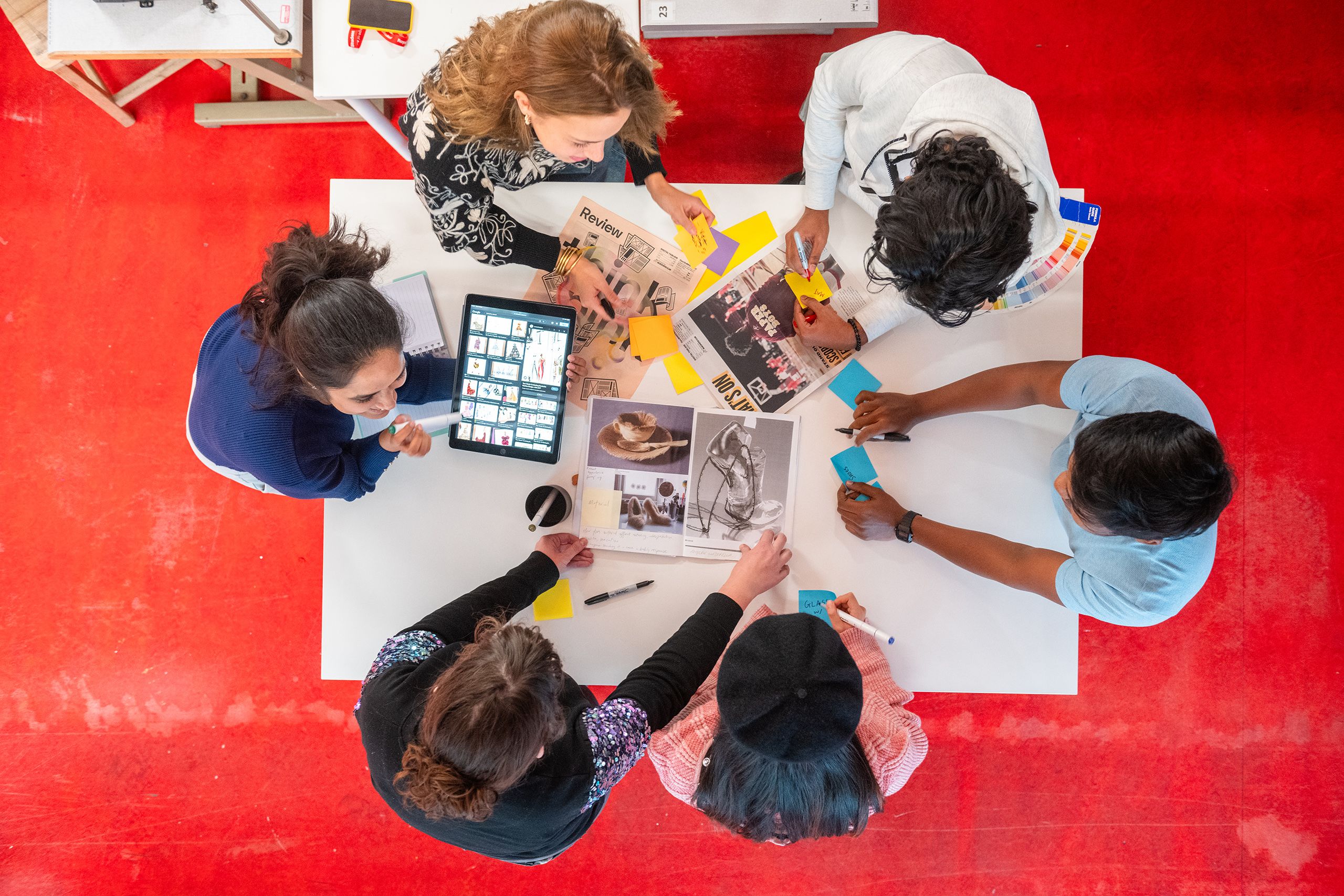 Arial view of students working together around a table, examining printed material
