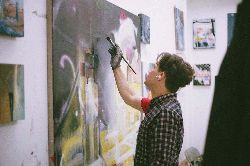A student painting a large canvas in the painting studios