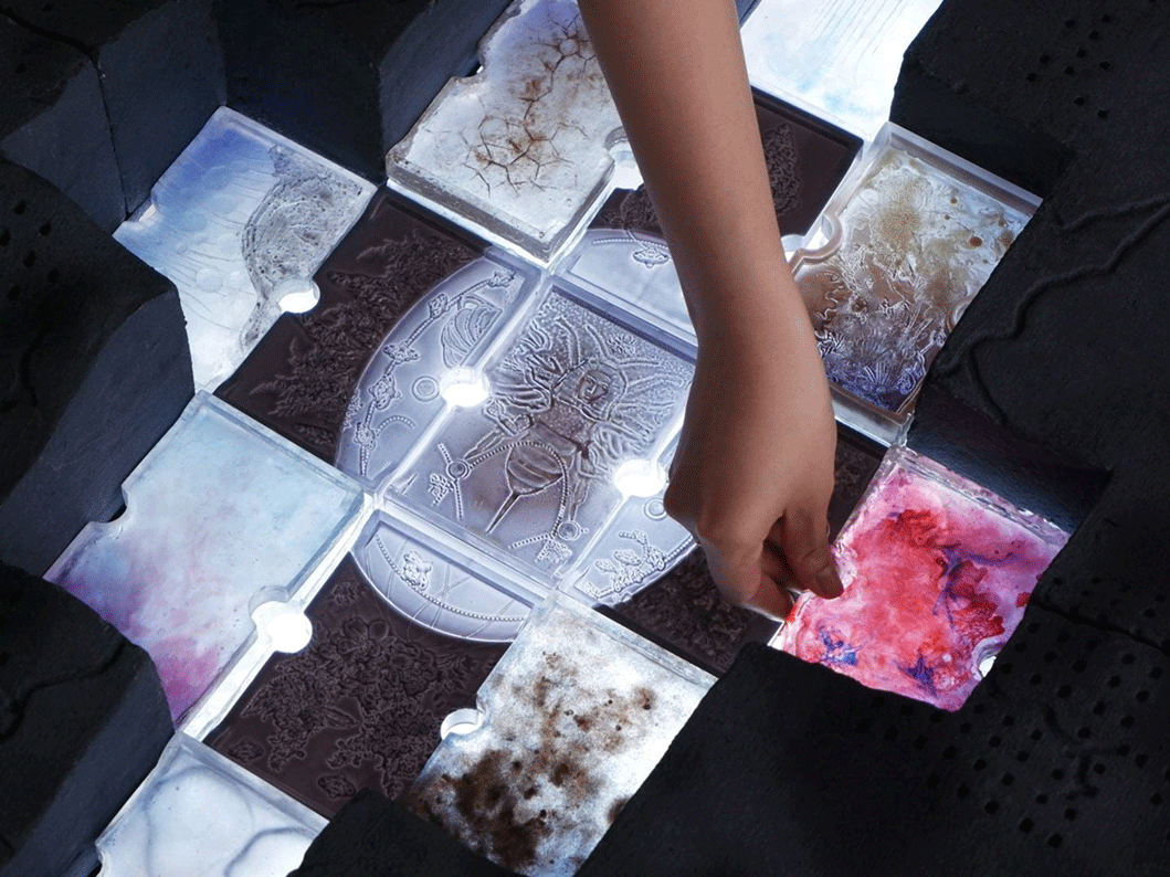 A hand places tiles featuring images of ceramics and materials