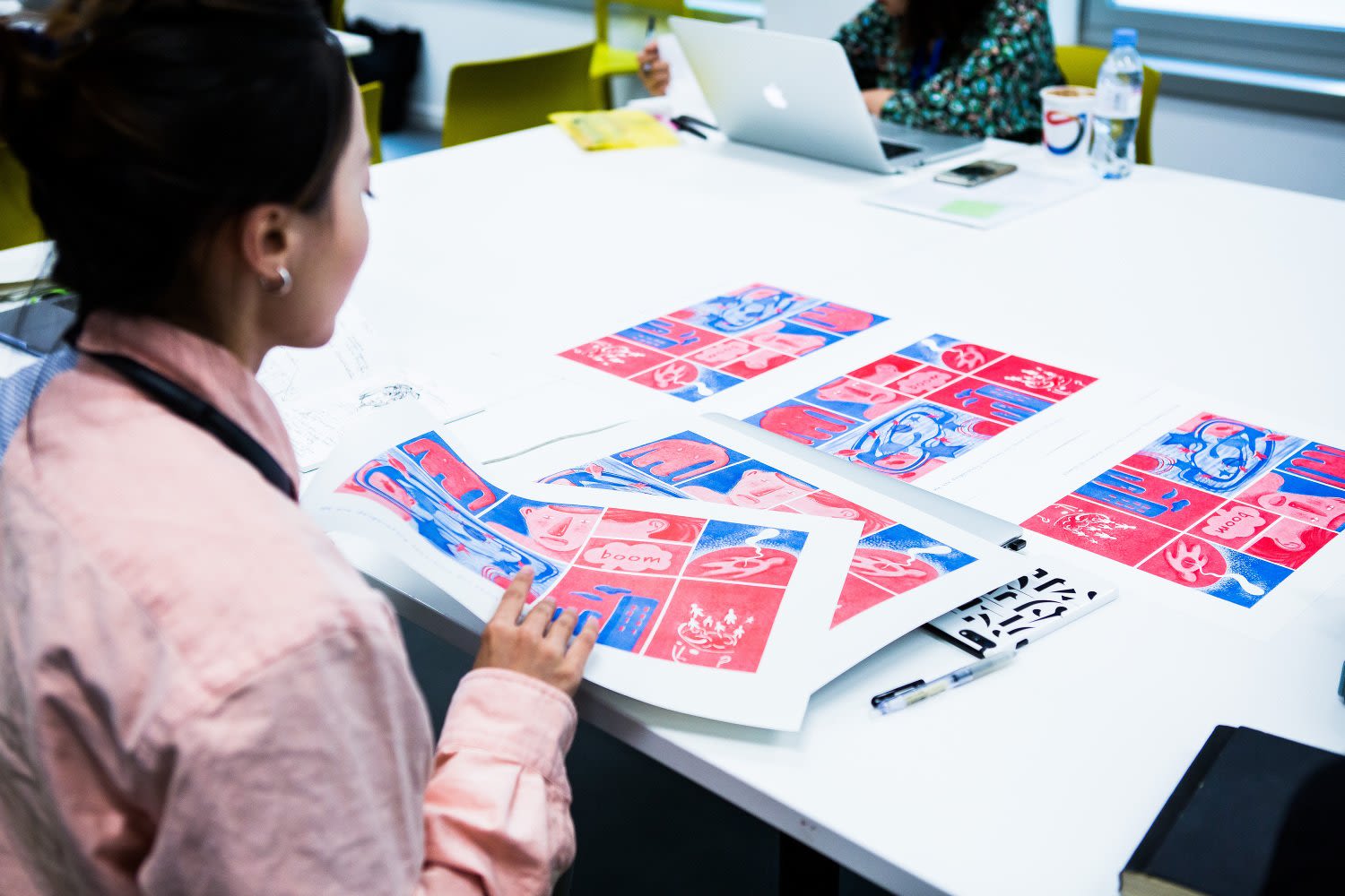 A participant sits at a desk looking through sketches for a graphic novel.
